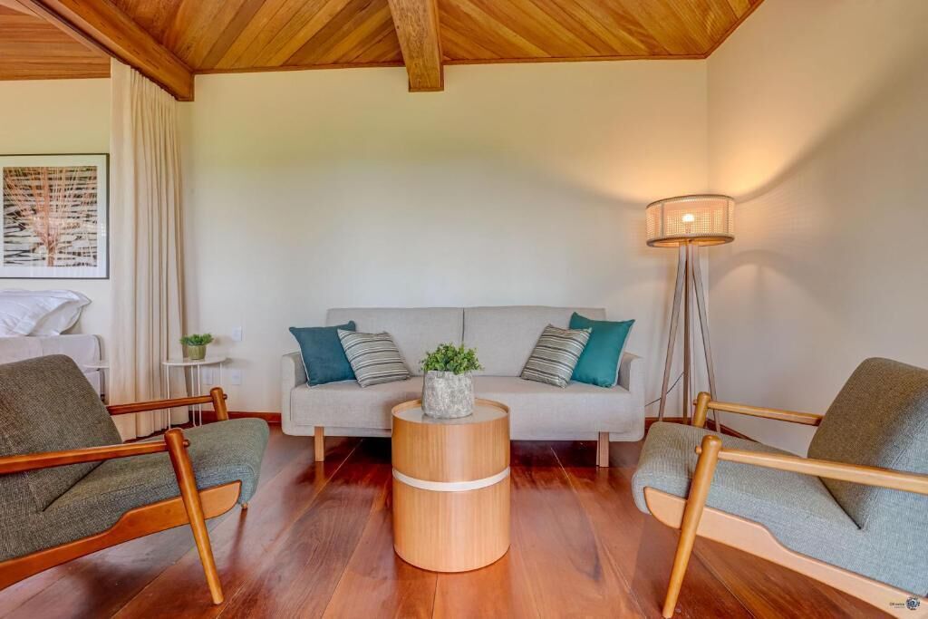 Una sala de estar con un sofá, dos sillones, una mesa de centro de madera y una lámpara de pie.