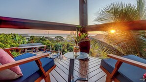 A terrace with a view of the ocean, wooden furniture, and a table with a vase. - Chocolate Hotel (Itacaré)