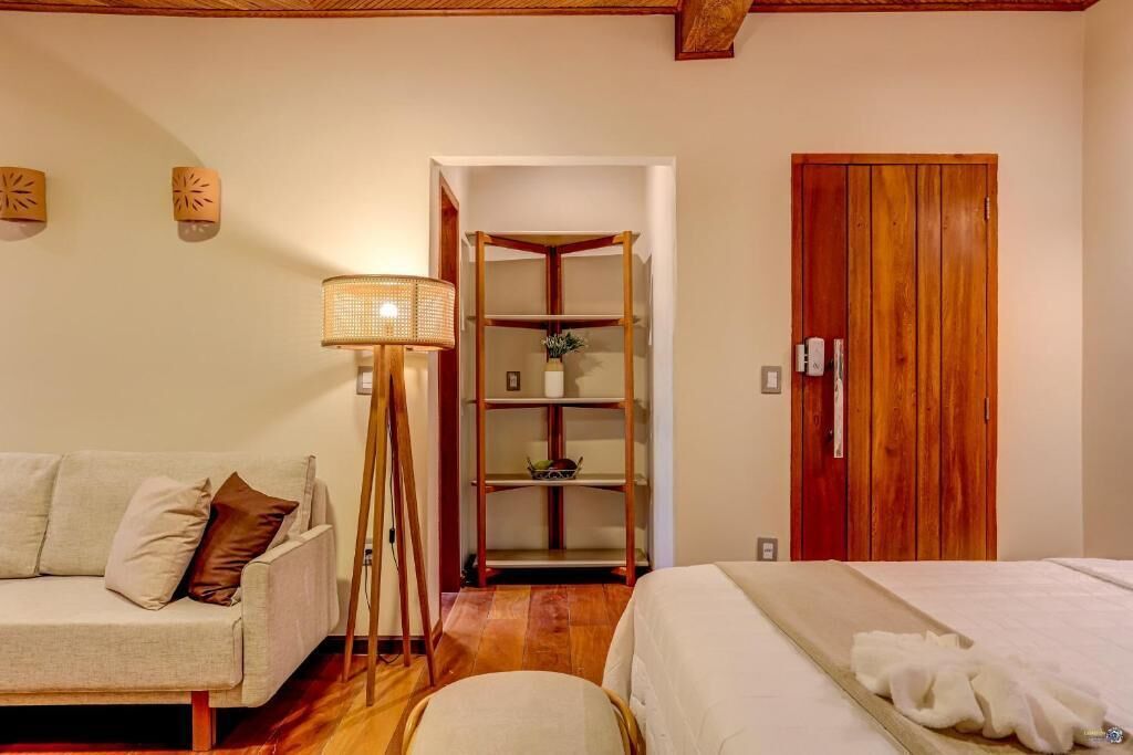 Un dormitorio con sofá, mesita de noche, lámpara, armario de madera y estantería.