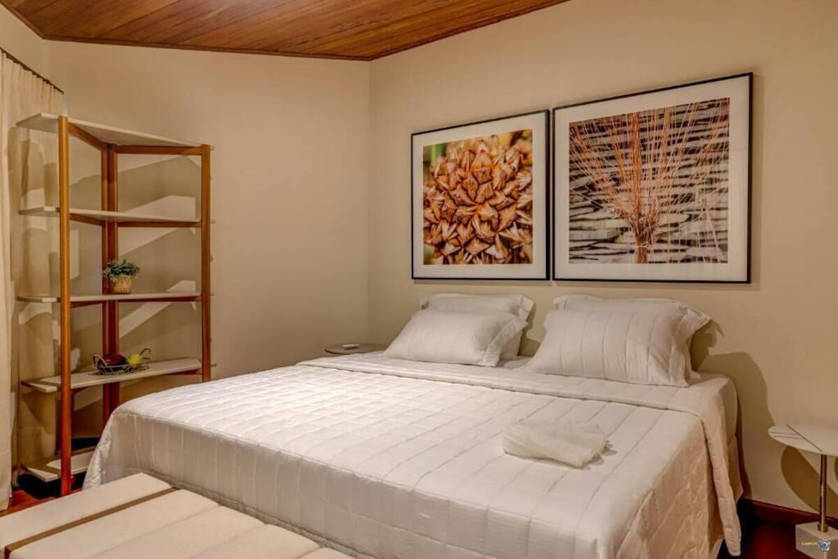 Una camera da letto con un letto, una scaffalatura in legno e due quadri appesi al muro.