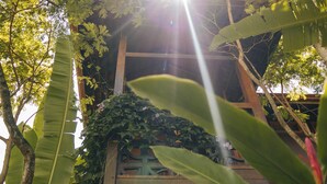 A building with a wooden structure, surrounded by lush green foliage and a hanging woven basket. - Chocolate Hotel (Itacaré)