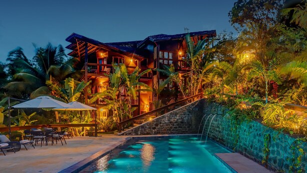A multi-story resort with a swimming pool, surrounded by lush tropical vegetation. - Chocolate Hotel (Itacaré)