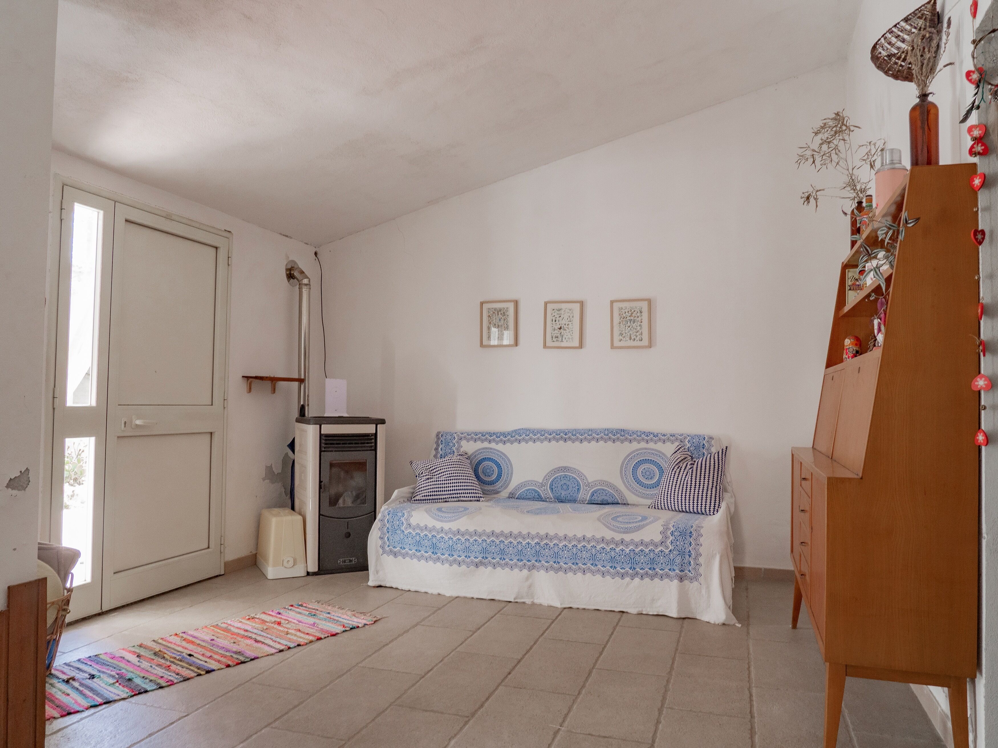 Una habitación con una cama, un calentador, un armario de madera y una puerta.