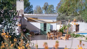 A patio with outdoor furniture, a pool, and a garden area with various plants and flowers. - Domu Prexada (Maracalagonis)