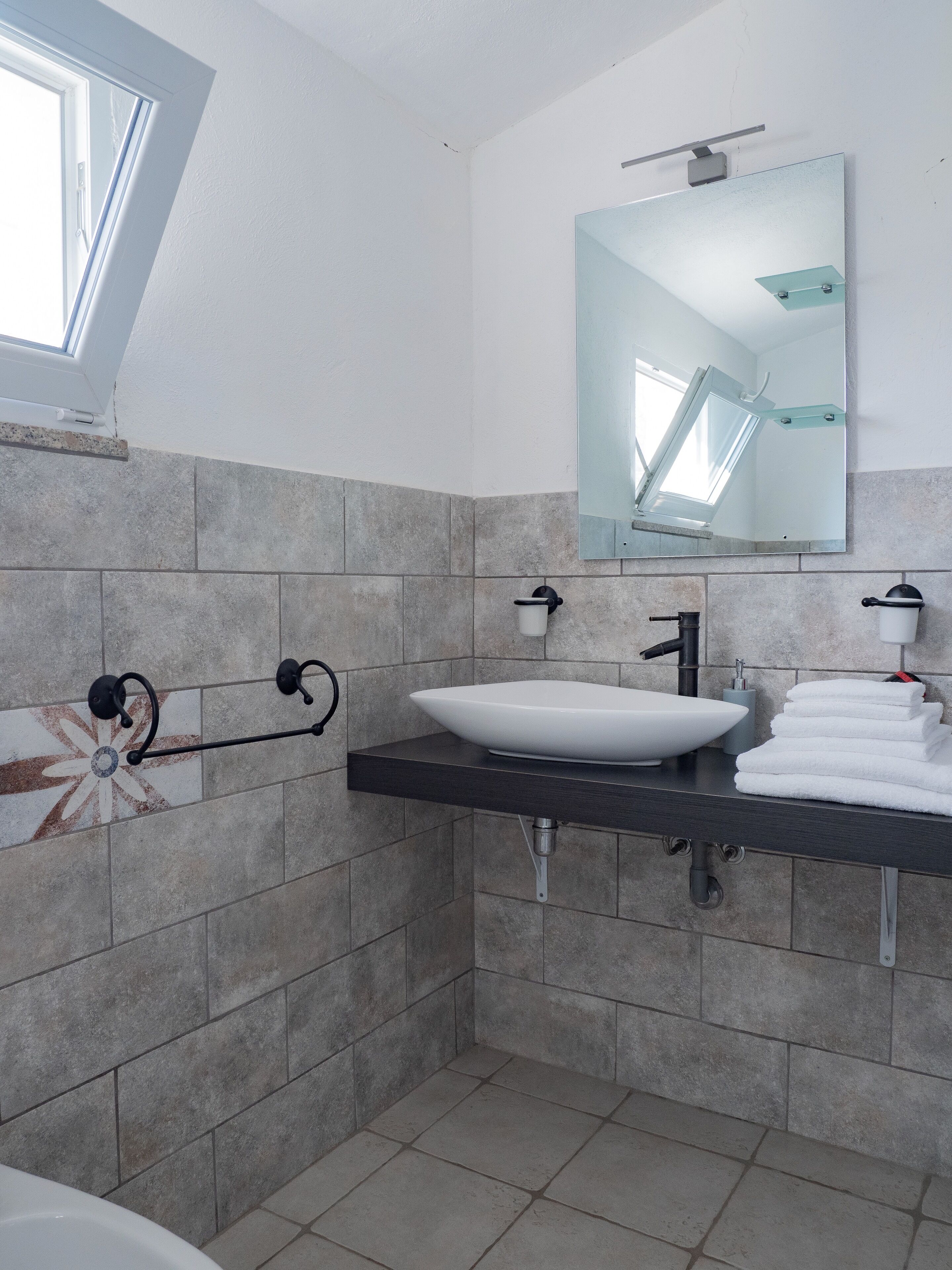 A modern bathroom with a large mirror, a white sink, and a towel rack.