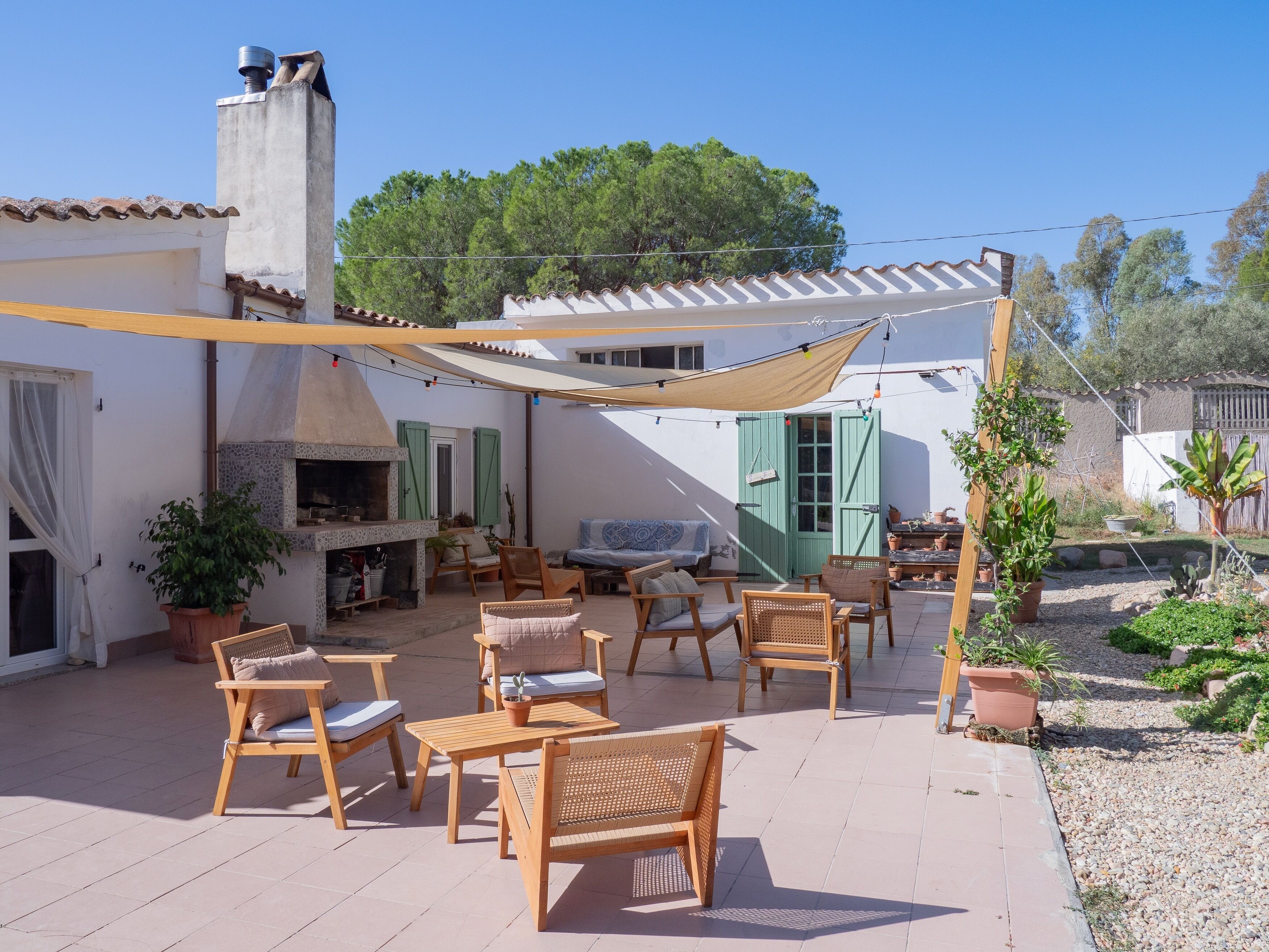 An outdoor patio with wooden furniture, a barbecue area, and a pergola providing shade.