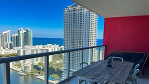 A balcony with a wooden table and chairs, overlooking a cityscape and water. - 37a Exceptional 2 bedroom PH Incredible View (Hallandale Beach)