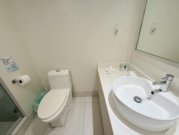Une petite salle de bain propre, équipée de toilettes, d’un lavabo et d’un miroir.