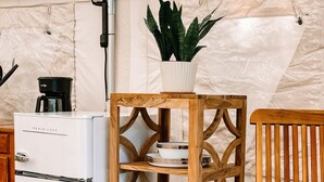Un petit espace cuisine comprenant un réfrigérateur blanc, un meuble de rangement en bois et une chaise.
