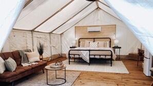 Une tente équipée d’un lit, d’un canapé, d’une petite table et d’une lampe.