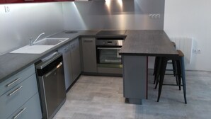 Een moderne keuken met roestvrijstalen apparatuur, een inbouwoven en een grijs aanrecht.