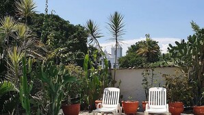 A rectangular pool with a tiled edge, surrounded by potted plants and two white lounge chairs. - Andorinhas (Niteroi)