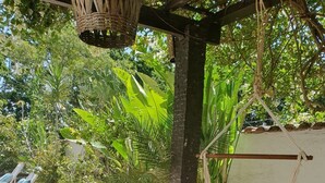 A patio area with a checkered table, potted plants, a hammock, and a stone-tiled floor. - Andorinhas (Niteroi)