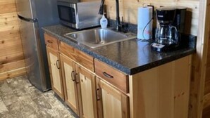 A compact kitchen with wooden cabinets, a stainless steel refrigerator, a microwave, a sink, and a coffee maker. - Cabin   13 (Hamilton)