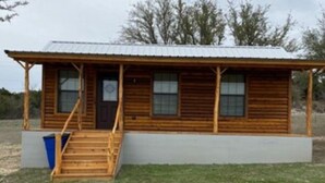 A wooden cabin with a porch and a single staircase leading to the entrance. - Cabin   13 (Hamilton)