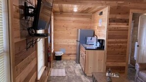 En smal træhytte med et tekøkken, et lille bord og en sofa.