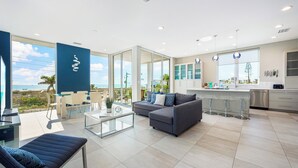 Ein modernes Wohnzimmer mit einer Couch, einem Glastisch und Blick aufs Meer.
