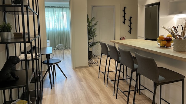 Een moderne keuken met een houten aanrecht, barstoelen en een koelkast.