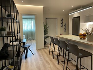 A modern kitchen with a wooden countertop, bar stools, and a refrigerator.