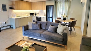 Een moderne woonkamer met een grijze bank, een salontafel en een eethoek met een tafel en stoelen.