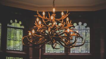 Un candelabro con múltiples luces, en una habitación con ventanas amplias y ambiente oscuro.