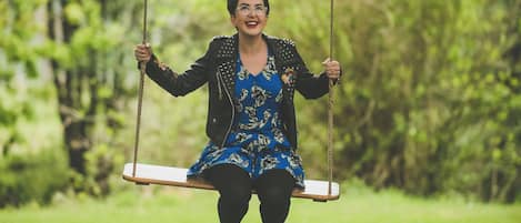 A person on a swing in a park with greenery in the background.