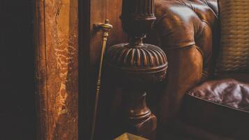 Una puerta de madera con picaporte de latón, un candelabro de bronce y un sofá de cuero con un cojín.