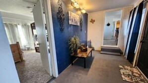 A hallway with a blue accent wall, a wooden bench with plants, and a light fixture. - Rustic retreat-near the Canyon (Canyon)