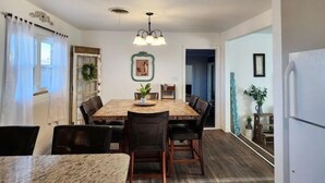 A dining area with a wooden table and chairs, a chandelier, and a view into another room. - Rustic retreat-near the Canyon (Canyon)