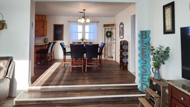 A dining area with a wooden floor, a table with chairs, and a chandelier. There is a staircase leading to another room. - Rustic retreat-near the Canyon (Canyon)