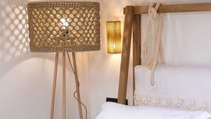 A bed with a wooden headboard and ropes, a woven floor lamp, and a wall-mounted light fixture.