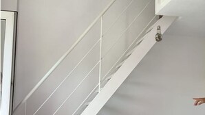 Un escalier moderne avec des rampes blanches et un luminaire.