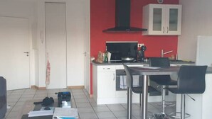 Un espace de vie compact comprenant un coin cuisine, un coin repas et un coin salon.