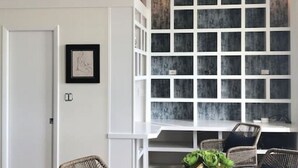 A dining area with a round table, wicker chairs, and a large window with multiple panes. - 5-star Luxury Apartment - Atop the Seagle Building (Gainesville)