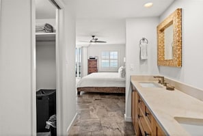 A modern bathroom with a stone floor, a large mirror, and a built-in sink. - Gorgeous 2 Bed 2 Bath Gulf front, just steps to the white powder beach (Siesta Key)