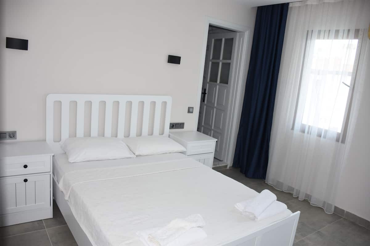 A neatly arranged bedroom with a bed, bedside tables, and a door leading to another room.
