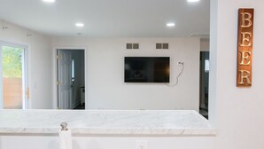 A modern kitchen with a marble countertop, a flat-screen TV mounted on the wall, and a wooden sign with the letters "BEER". - Updated Ann Arbor ranch w/private yard and lots of parking!  (Ann Arbor)
