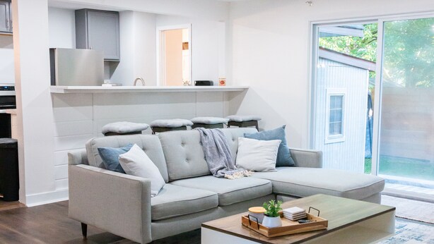 A modern living room with a grey sectional sofa, a coffee table, and a large window. - Updated Ann Arbor ranch w/private yard and lots of parking!  (Ann Arbor)