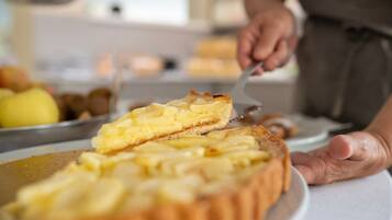 A person cutting a pie with a golden crust, likely apple pie, on a white plate.