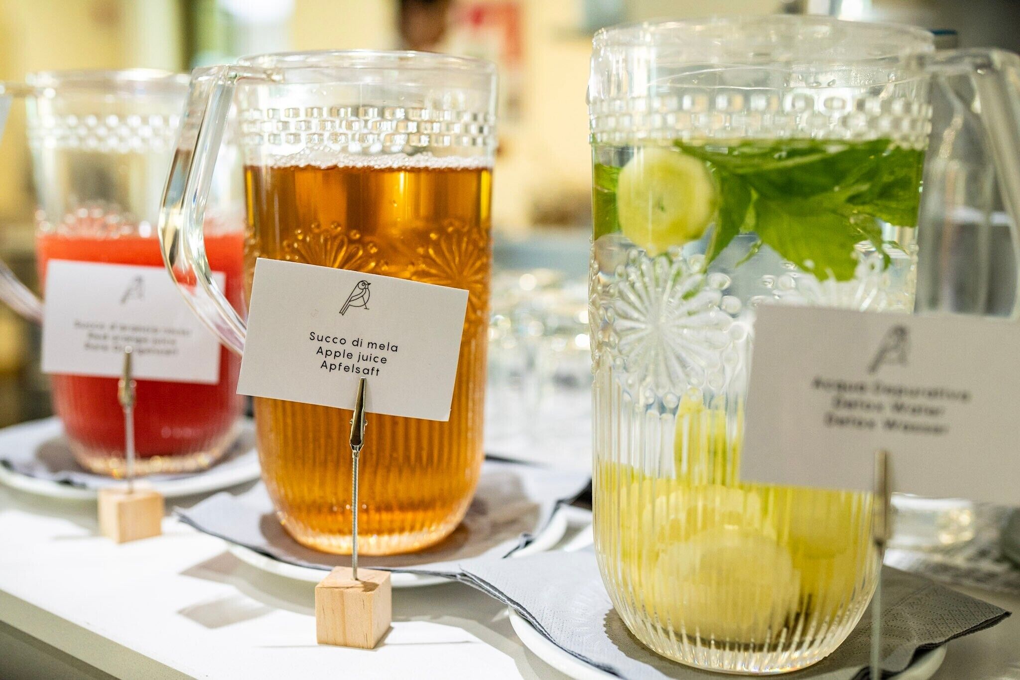 Three glass containers with labels, each containing a different beverage.