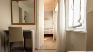 Une chambre d’hôtel équipée d’un bureau, d’une chaise, d’un lit et d’un grand miroir.