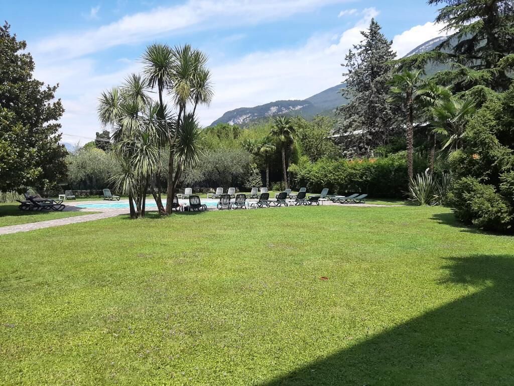 Un espace extérieur verdoyant, avec des chaises longues et une piscine, entouré d’arbres et de montagnes.