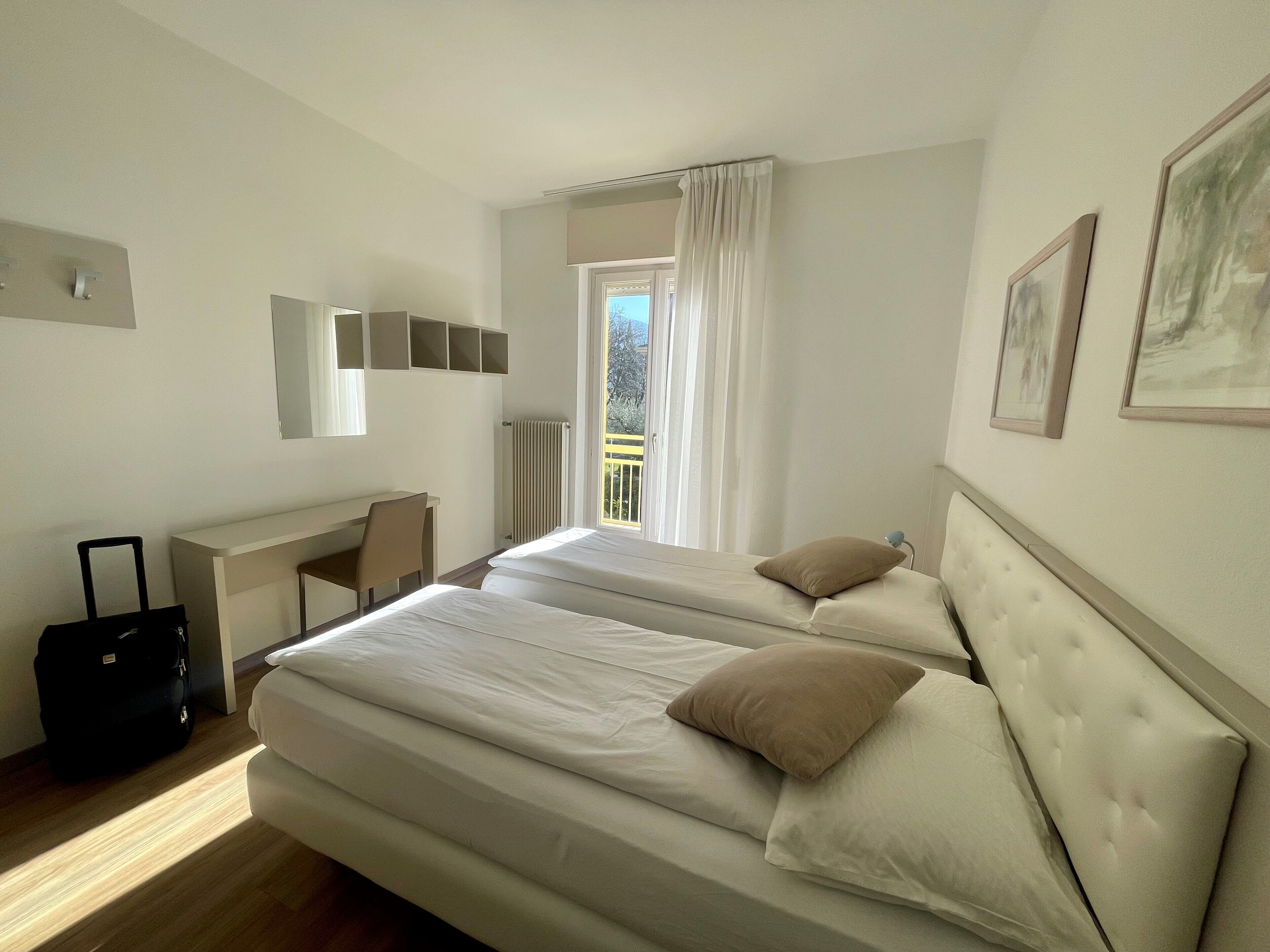 A hotel room with two beds, a desk, and a chair.