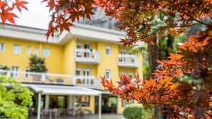 Un bâtiment jaune doté de nombreux balcons et d’un espace extérieur aménagé avec des sièges, protégé par un auvent.