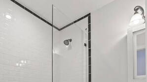 A bathroom with a glass-enclosed shower, a white toilet, and a sink with a mirror.