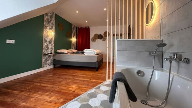 Une chambre moderne avec un grand lit, une douche à l’italienne et une fenêtre de toit.