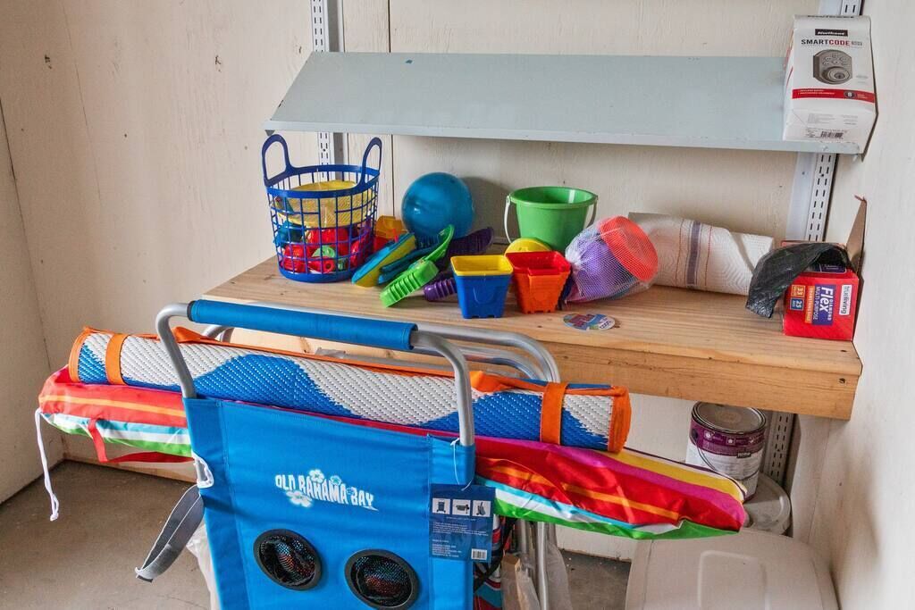 A storage area with a blue beach chair, a blue basket, and various colorful plastic containers.