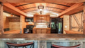 Una cocina rústica de madera con una isla central, armarios de madera y una zona de bar con taburetes.
