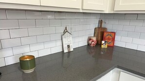Une cuisine avec des meubles blancs, un plan de travail gris et un lave-vaisselle.
