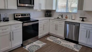 A modern kitchen with white cabinets, stainless steel appliances, and patterned rugs. - Charming 2 bed in Westminster (Westminster)